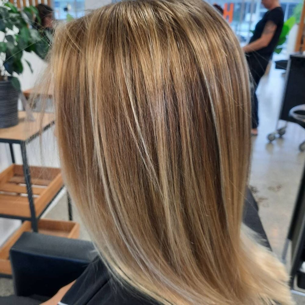 Shoulder-length soft blonde balayage from behind, in the salon chair.